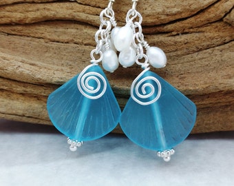 May include: Teal blue glass earrings with silver wire detailing and white pearl accents.