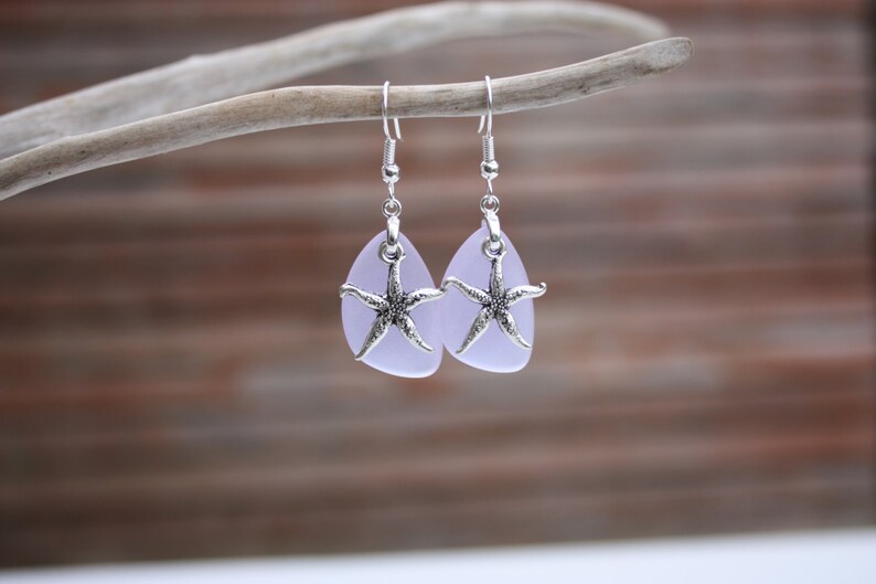 Puede incluir: Un par de pendientes de plata con forma de l&aacute;grima de vidrio lavanda y un dije de estrella de mar de plata.