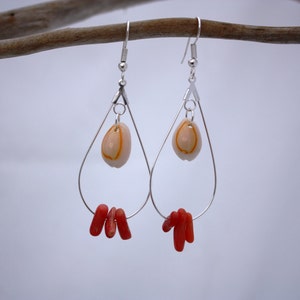 May include: Silver teardrop earrings with a small white shell and red coral accents.