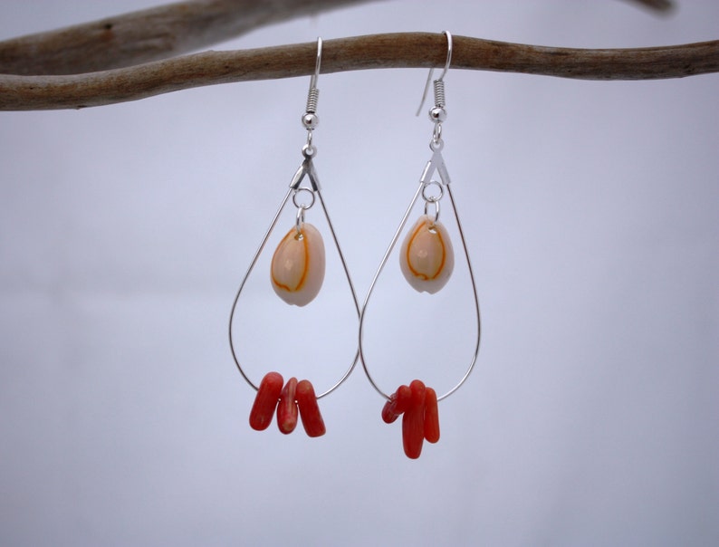 May include: Silver teardrop earrings with a small white shell and red coral accents.