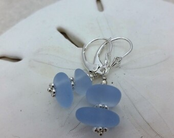 May include: A pair of silver dangle earrings with light blue glass beads. The earrings have a leverback closure.