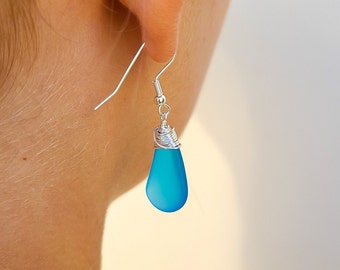 May include: Silver dangle earrings with a light blue teardrop-shaped gemstone.