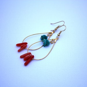 May include: Gold dangle earrings with turquoise and coral accents. The earrings feature a teardrop shape with a small loop at the top for hanging.