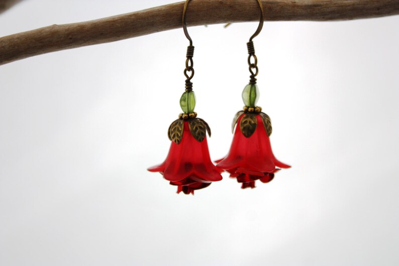 May include: Red flower shaped earrings with green accents and bronze details.