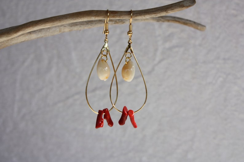 May include: Gold teardrop earrings with a white shell charm and red coral accents.