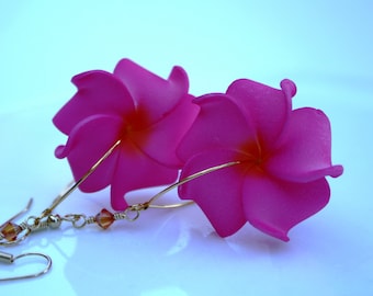 Puede incluir: Un par de pendientes de flores rosas con alambre dorado y una pequeña cuenta de cristal.