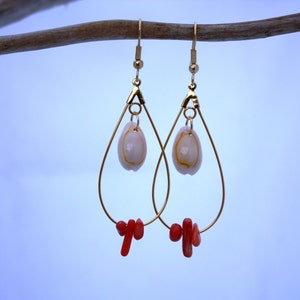 May include: Gold teardrop earrings with a white shell charm and red coral accents.