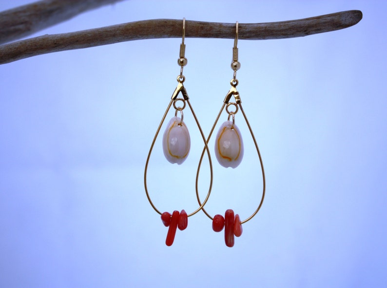 May include: Gold teardrop earrings with a white shell charm and red coral accents.