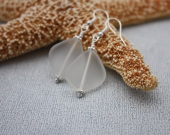 May include: A pair of silver earrings with frosted white glass teardrop-shaped pendants.
