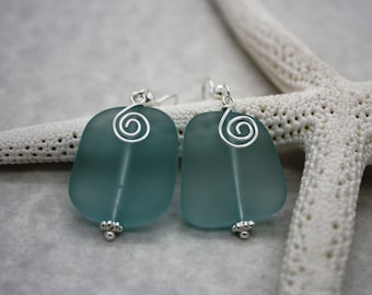 May include: A pair of teal blue sea glass earrings with silver wire spirals and silver beads.