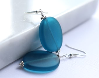 May include: Teal blue oval shaped glass earrings with silver hooks.