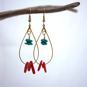 May include: Gold teardrop earrings with turquoise and coral accents. The earrings are hanging from a branch.