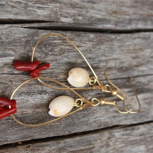May include: Gold hoop earrings with a white shell charm and a red coral charm hanging from each hoop.
