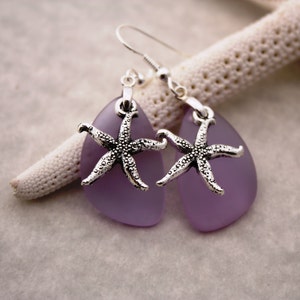 Puede incluir: Un par de pendientes de plata con colgantes de l&aacute;grima de vidrio morado y abalorios de estrella de mar plateados.