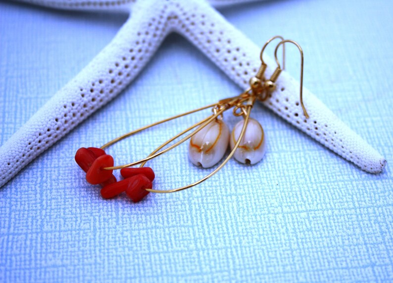 May include: Gold dangle earrings with red coral beads and white shell accents.