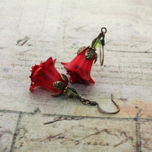 May include: Red flower-shaped earrings with green accents and bronze hooks.