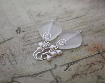 May include: A pair of silver earrings with frosted glass teardrop shapes and pearl accents.