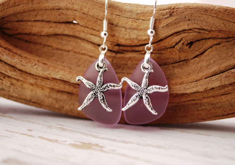 Puede incluir: Un par de pendientes colgantes con forma de l&aacute;grima de vidrio morado y un dije de estrella de mar plateado.