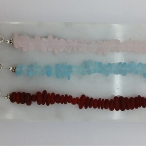 Pu&ograve; includere: Tre braccialetti in vetro di mare con ciondoli a forma di stella marina argentati e chiusure a scorrimento. I braccialetti sono realizzati in vetro di mare rosa, blu e rosso.
