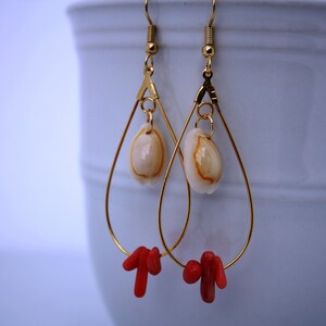 May include: Gold teardrop earrings with a white seashell charm and red coral accents.