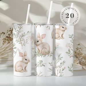May include: Three white tumblers with bunny and floral designs. Each tumbler has a white straw and a lid. The tumblers are decorated with watercolor illustrations of bunnies and greenery. The text "20 TUMBLER DESIGNS INCLUDED" is on one of the tumblers.