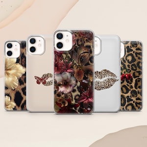 May include: A collection of five phone cases with various designs. The cases feature floral, leopard print, and lip motifs. One case displays a butterfly design, and another showcases cherries. The cases are in clear protective covers.
