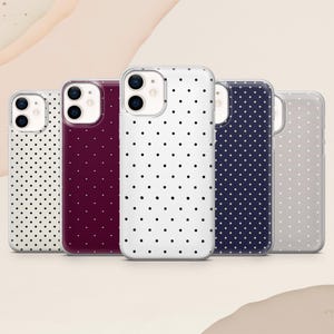 Puede incluir: Cinco fundas de teléfono en fila, cada una con un color y un patrón de lunares diferente. Las fundas son blancas, burdeos, blancas, azul marino y grises. Los lunares son negros y están espaciados uniformemente.