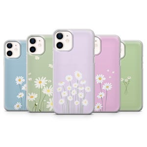 May include: A collection of five phone cases in pastel colors: blue, green, lavender, pink, and light green. Each case features a white daisy floral design. The cases are made of a clear, protective material.