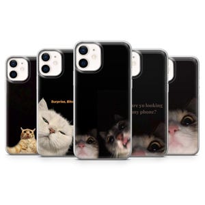 Puede incluir: Cinco fundas de teléfono con fondos negros y diferentes caras de gato. Una funda tiene el texto "Surprise, Bitch". Otra funda tiene el texto "are yo looking at my phone?"