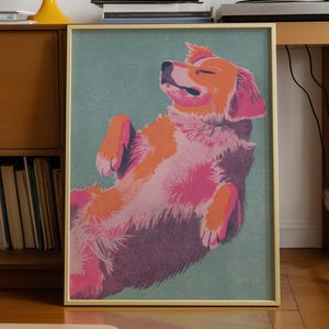 May include: A framed art print featuring a stylised illustration of a dog lying on its back with eyes closed. The dog is rendered in shades of orange, pink, and dark purple against a muted teal background. The frame is a thin, metallic gold colour.