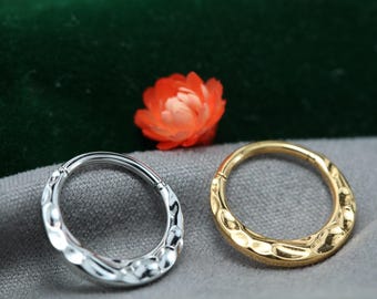 May include: Two textured metal hoop earrings. One is silver-colored, the other is gold-colored. The earrings are circular with a hammered design. An orange flower is in the background.