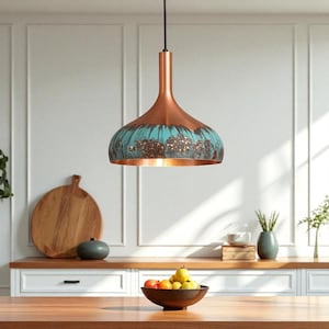 Op de afbeelding: Een koperkleurige hanglamp met een turquoise en bruin patroon hangt boven een houten tafel. De lamp is opgehangen aan een zwart snoer. Een houten snijplank en een fruitschaal zijn zichtbaar op de achtergrond.