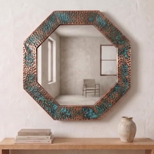 May include: An octagonal wall mirror featuring a hammered copper frame with a distinct verdigris patina. The frame displays a textured, dimpled surface with alternating metallic copper tones and oxidized teal green accents throughout the border.