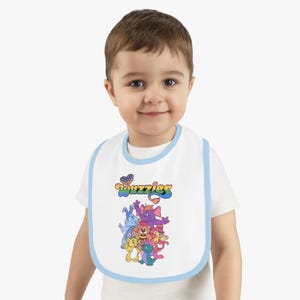 Babero de bebé Wuzzles con ribete en contraste. Bonito babero colorido, accesorio de alimentación divertido, regalo para bebés pequeños y baby shower.