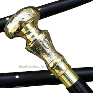 Puede incluir: Bastón decorativo con empuñadura de latón y caña de madera negra. El mango está intrincadamente diseñado con patrones florales. El bastón es un accesorio elegante y una ayuda funcional.