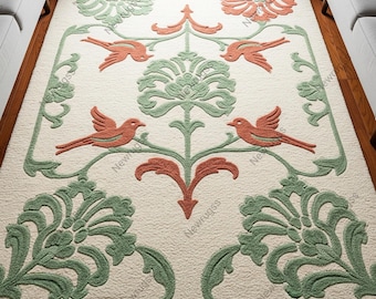 May include: A cream-coloured area rug with a detailed floral and bird design. The rug features green and coral-coloured botanical and bird motifs. The design includes stylised flowers, leaves, and birds, creating a decorative pattern. The rug is placed on a wooden floor.