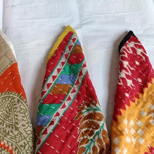 Puede incluir: Tres piezas de tela plegadas con patrones y costuras coloridas. Las telas presentan tonos de naranja, rojo, amarillo, verde y marr&oacute;n. Las costuras blancas crean un efecto de contraste. Los art&iacute;culos est&aacute;n dispuestos sobre una superficie blanca.