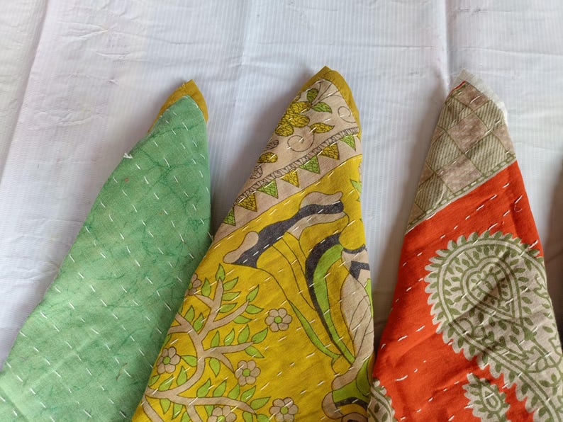 Puede incluir: Primer plano de tres piezas de tela triangulares de colores. Una es verde, otra amarilla con un dise&ntilde;o floral y la tercera naranja con un estampado de cachemira. Todas las piezas tienen costuras blancas y ribete amarillo.