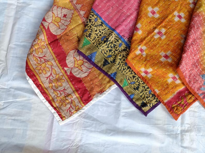 Pode incluir: Close-up de v&aacute;rios peda&ccedil;os de tecido coloridos e estampados. Os tecidos apresentam desenhos florais e geom&eacute;tricos em tons de amarelo, vermelho, rosa e laranja, com bordas decorativas. As pe&ccedil;as s&atilde;o costuradas, sugerindo um edredom ou arte t&ecirc;xtil.