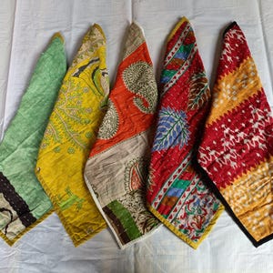 Puede incluir: Cinco piezas de tela estampada con motivos florales y cachemir, en tonos verdes, amarillos, naranjas y rojos, dispuestas sobre una superficie blanca. Los bordes tienen borduras contrastantes, midiendo aproximadamente 30 cm.