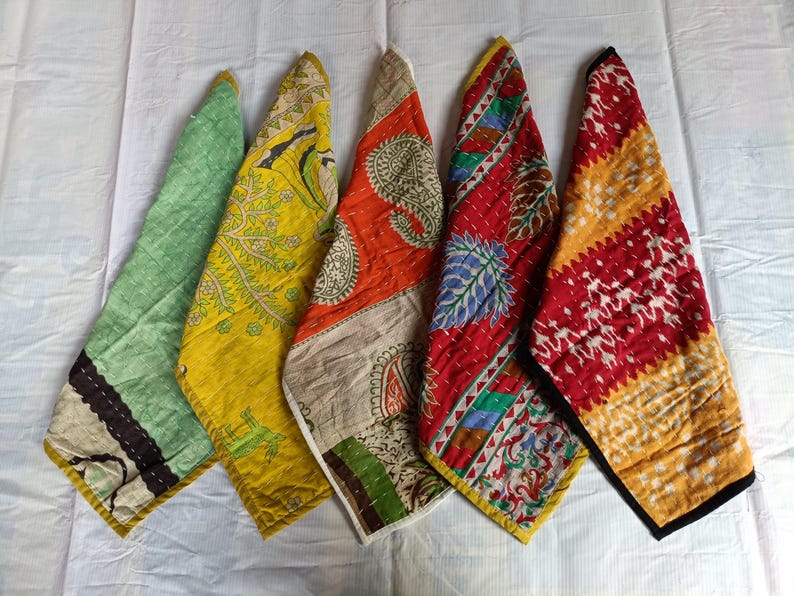 Puede incluir: Cinco piezas de tela estampada con motivos florales y cachemir, en tonos verdes, amarillos, naranjas y rojos, dispuestas sobre una superficie blanca. Los bordes tienen borduras contrastantes, midiendo aproximadamente 30 cm.