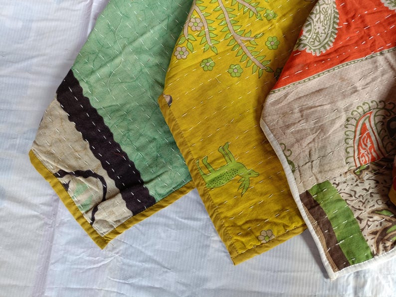 Puede incluir: Primer plano de tres piezas de tela coloridas y estampadas. Las telas presentan una variedad de colores, incluyendo verde, amarillo y naranja, con dise&ntilde;os y costuras intrincados. Las piezas probablemente forman parte de un proyecto textil m&aacute;s grande.