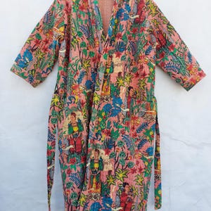 Può includere: Un accappatoio rosa fantasia con un design floreale e figurativo. L'accappatoio ha uno scollo a V, maniche lunghe e una cintura abbinata. Il tessuto presenta un mix di colori, tra cui rosa, verde, blu e giallo.