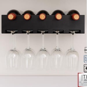 Könnte beinhalten: Ein schwarzes, an der Wand montiertes Weinregal mit fünf Weinflaschen und fünf Weingläsern. Das Regal hat Schlitze für die Flaschen und umgekehrte Schlitze für die Gläser. Die Weinflaschen haben Korken. Das Regal ist an einer weißen Wand montiert.