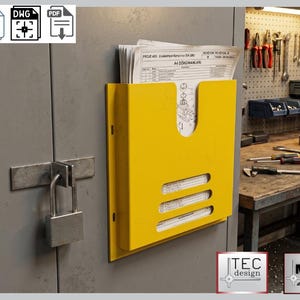 May include: A bright yellow wall-mounted document holder with three horizontal slots and a curved top. The holder is attached to a gray metal cabinet with a padlock. The holder contains several sheets of paper with text and diagrams.