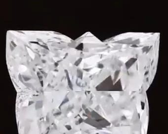 May include: A clear, princess-cut diamond with a unique, multi-faceted design. The diamond's shape is a modified square with a pointed top, and it reflects light, creating a brilliant sparkle against a black background.