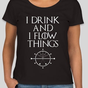 May include: Black t-shirt with the white text "I DRINK AND I FLOW THINGS" and a white graphic of a compass-like design. The shirt has a scoop neck and short sleeves.