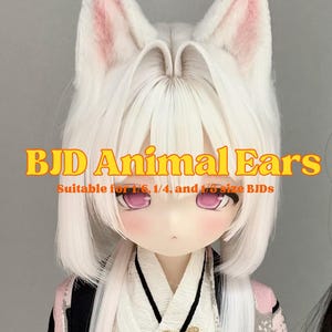 Puede incluir: Una muñeca con cabello blanco y grandes orejas de animal blancas con detalles internos rosados. La muñeca lleva un atuendo estilo kimono con un broche de mariposa dorado. El texto en la imagen dice "BJD Animal Ears" y "Suitable for 1/6, 1/4, and 1/3 size BJDs."