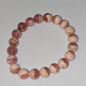 May include: A pink and white striped gemstone bracelet with round beads.
