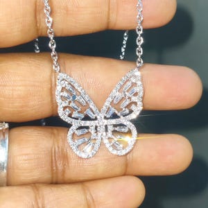 Peut inclure: Un collier pendentif papillon argent&eacute;. Le motif papillon est incrust&eacute; de petites pierres pr&eacute;cieuses transparentes. Les ailes sont orn&eacute;es de pierres de taille baguette et la cha&icirc;ne du collier est d&eacute;licate.